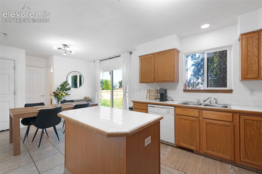 Image 12 of 31: Open-concept kitchen featuring wood-finish cabinetry, tile countertops, a b