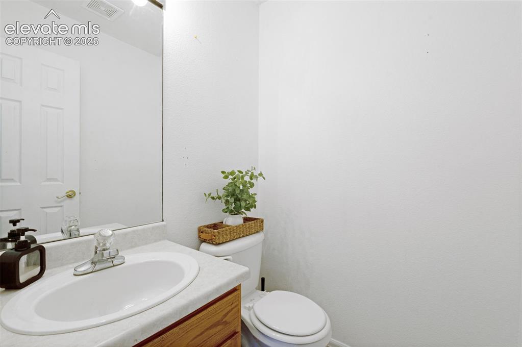 Image 14 of 31: White paneled door with brass-finish hardware, built-in vanity with laminat