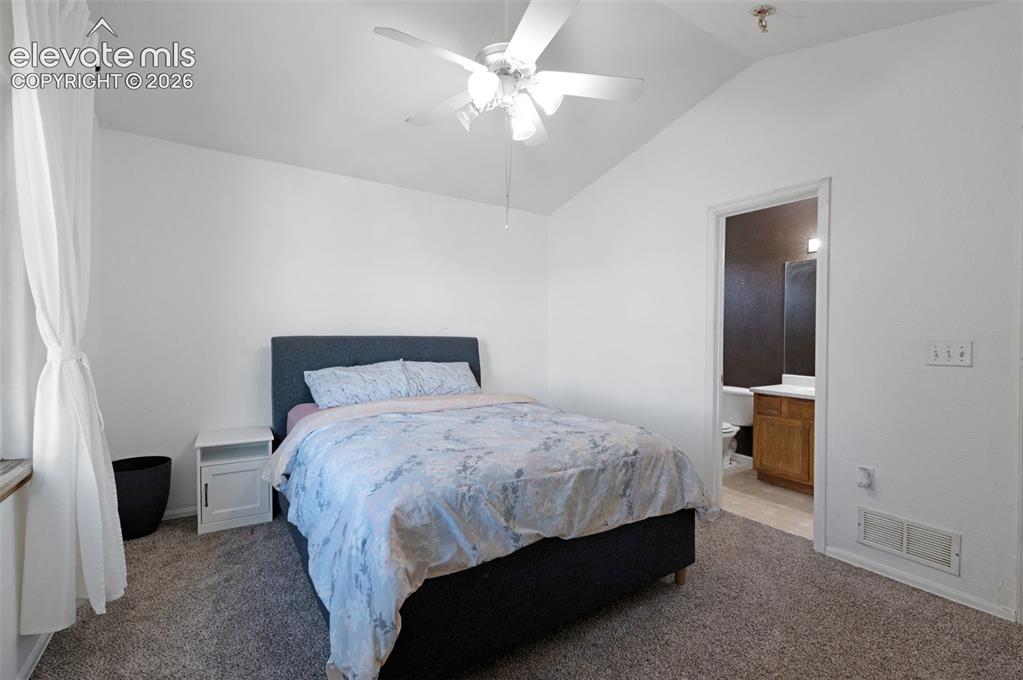 Image 16 of 31: Bedroom featuring vaulted ceilings with a ceiling fan, carpet flooring, and