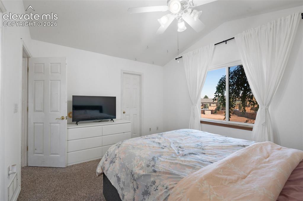 Image 18 of 31: Carpeted bedroom featuring a vaulted ceiling with a ceiling fan, a large wi