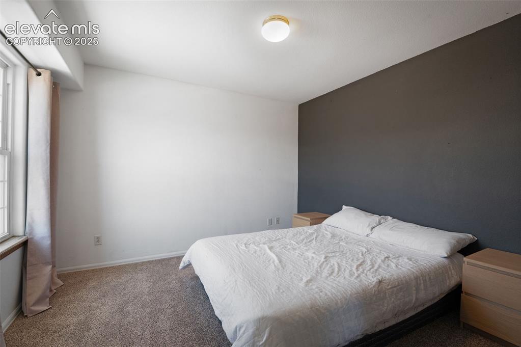 Image 24 of 31: Bedroom featuring a statement accent wall, carpeted flooring, and a window