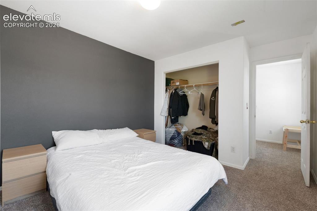 Image 25 of 31: Bedroom featuring a gray accent wall, neutral carpeting, and a built-in clo
