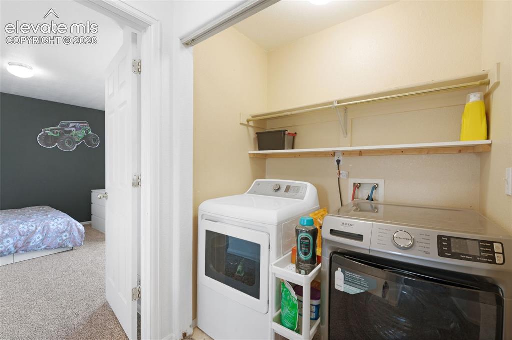 Image 27 of 31: Dedicated laundry closet featuring upper shelving and utility hookups