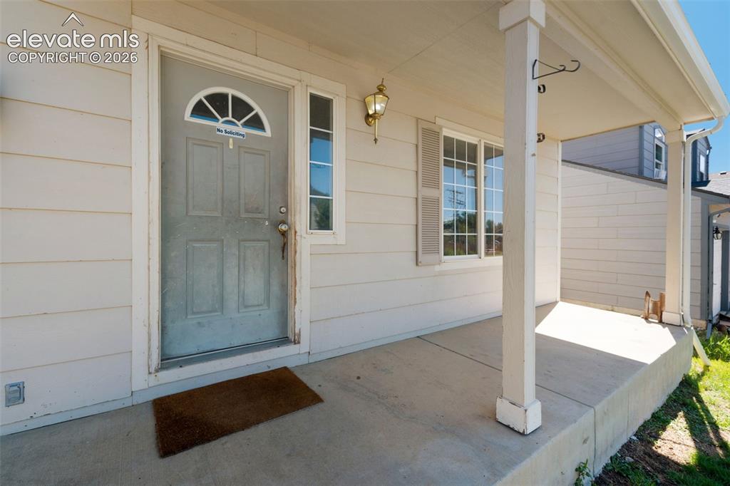 Image 4 of 31: Covered front porch featuring a paneled entry door with a decorative transo