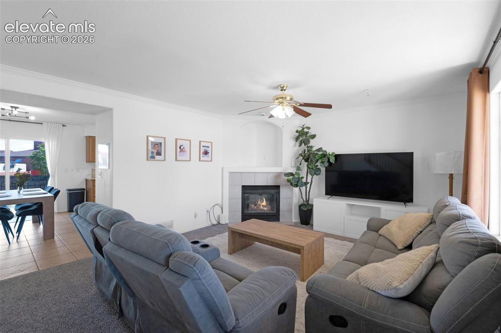 Image 5 of 31: Living area featuring a fireplace with a light-colored tile surround, a cei