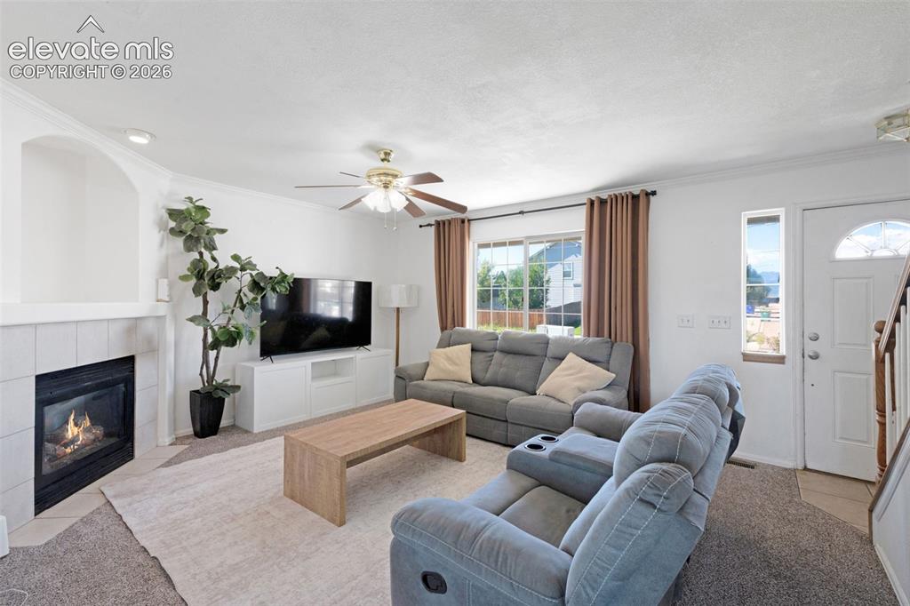 Image 6 of 31: Living area featuring a fireplace with a tiled surround, a large window wit