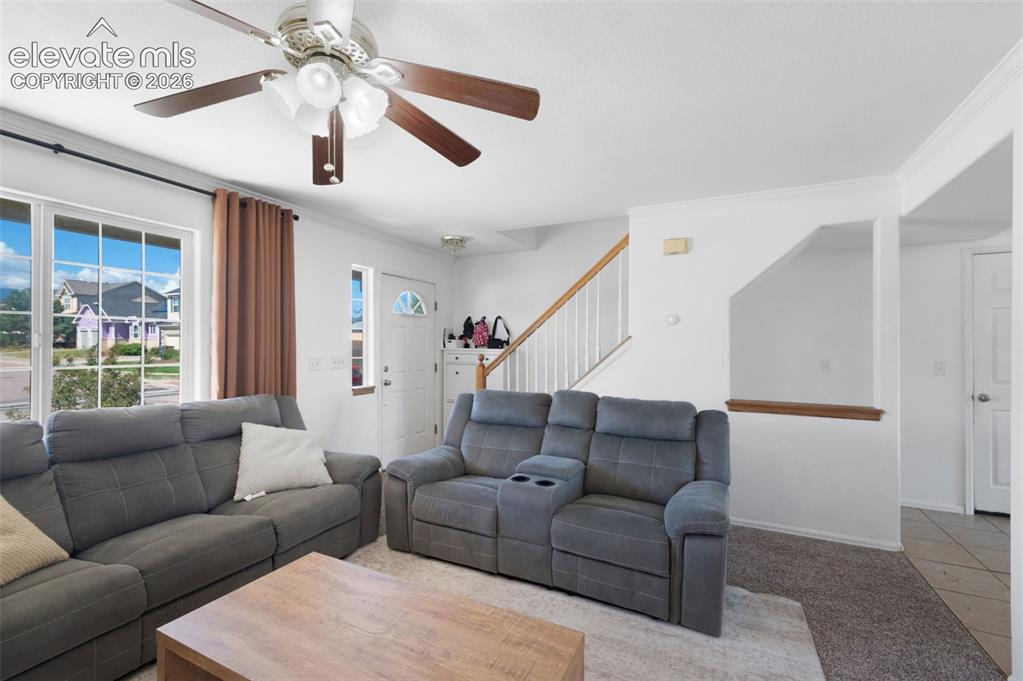 Image 7 of 31: Living area featuring a ceiling fan with integrated lighting, large window