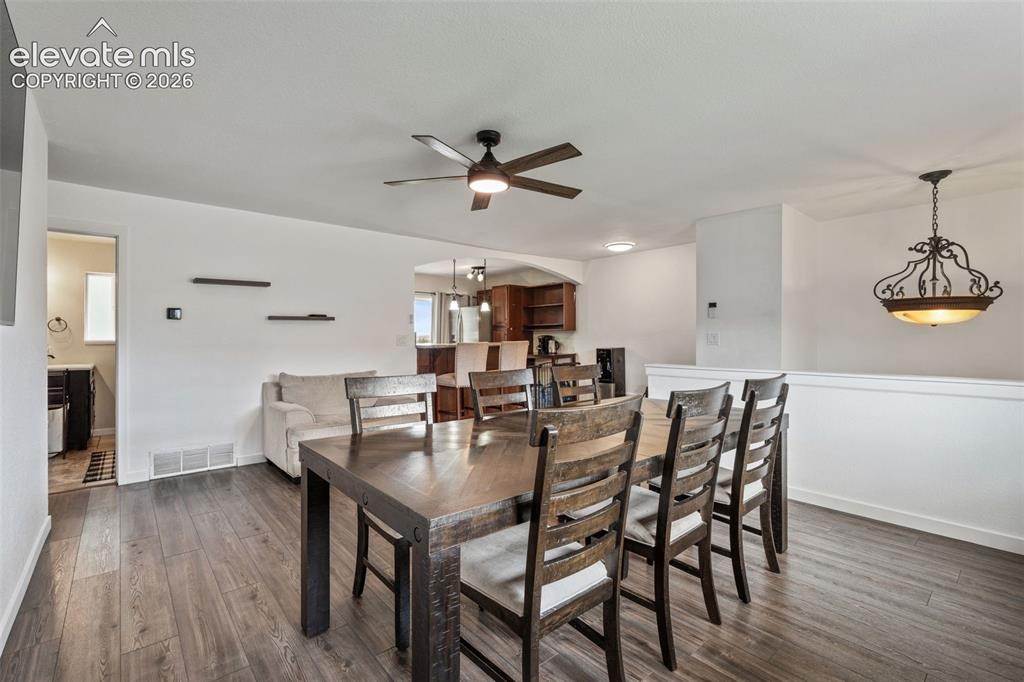 Image 11 of 43: Open-concept living area featuring wood-finish flooring, a ceiling fan with