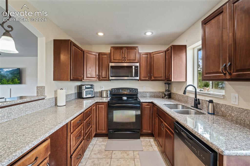 Image 13 of 43: U-shaped kitchen featuring brown cabinetry, light granite countertops, tile