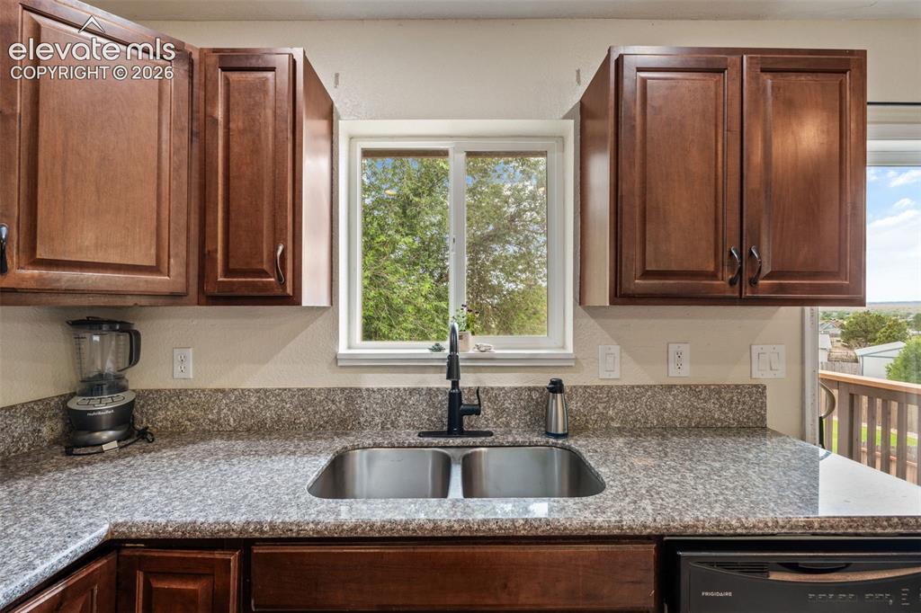 Image 14 of 43: Kitchen sink with a window overlooking mature trees, featuring a matte blac