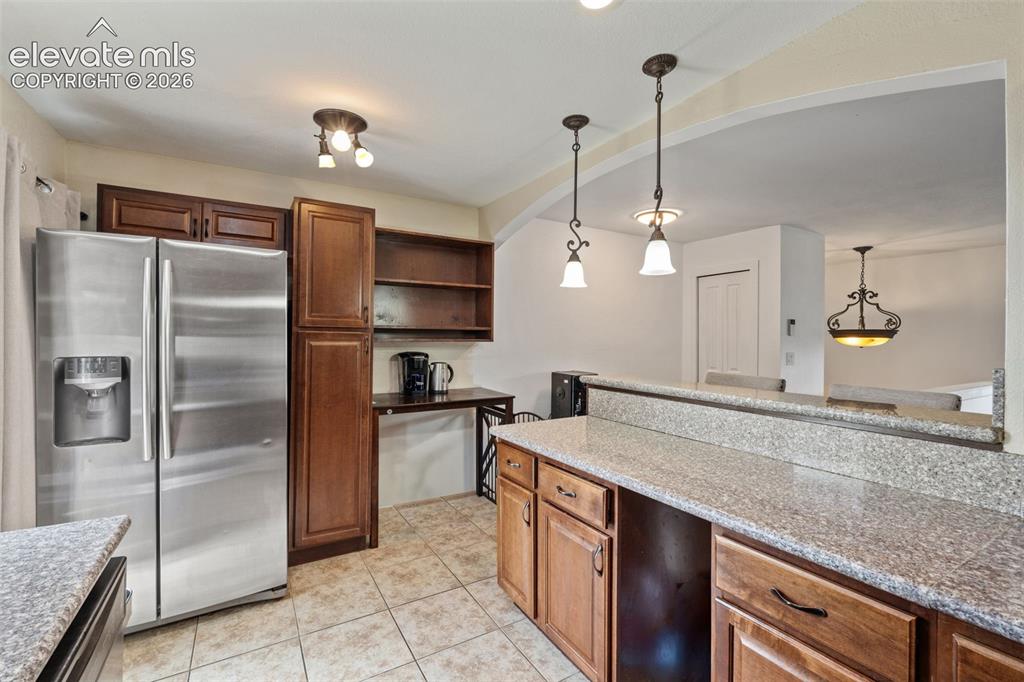 Image 15 of 43: Kitchen featuring granite-look countertops, medium-tone wood cabinetry, and