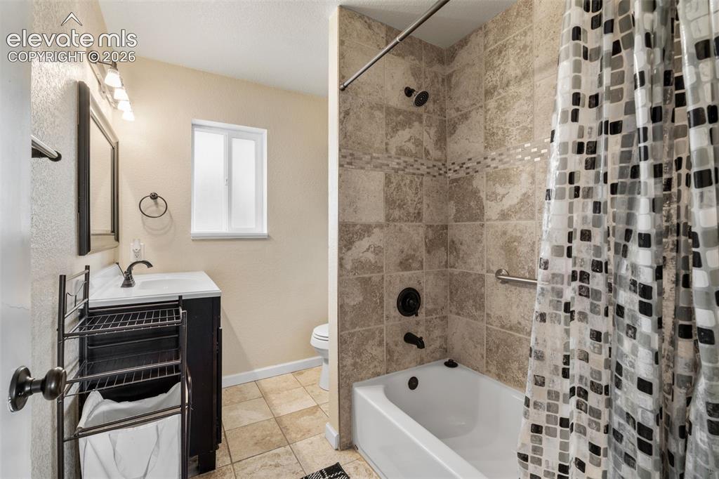 Image 20 of 43: Bathroom featuring a full tub and shower with tile surround, a dark wood-fi