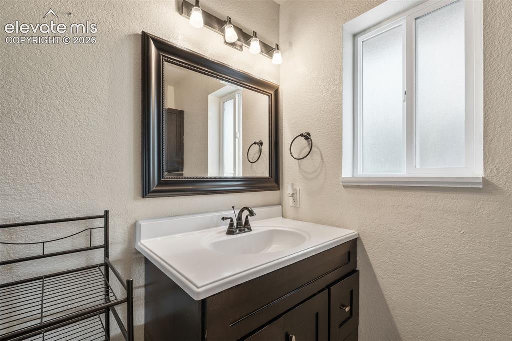 Image 21 of 43: Bathroom vanity with a dark wood-finish cabinet, white countertop, integrat