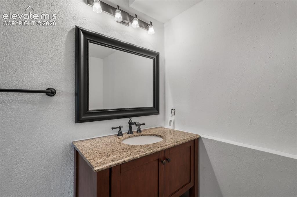 Image 27 of 43: Bathroom vanity featuring a granite countertop with an undermount sink, dar