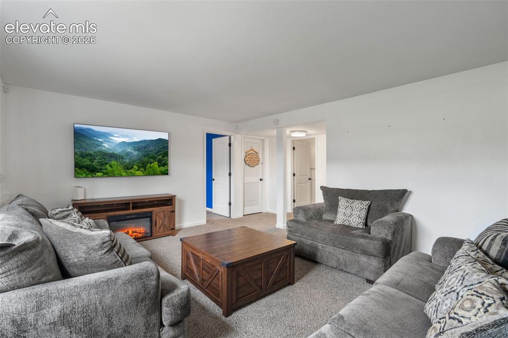 Image 3 of 43: Living area with light gray carpeting, crisp white walls, and white trim
