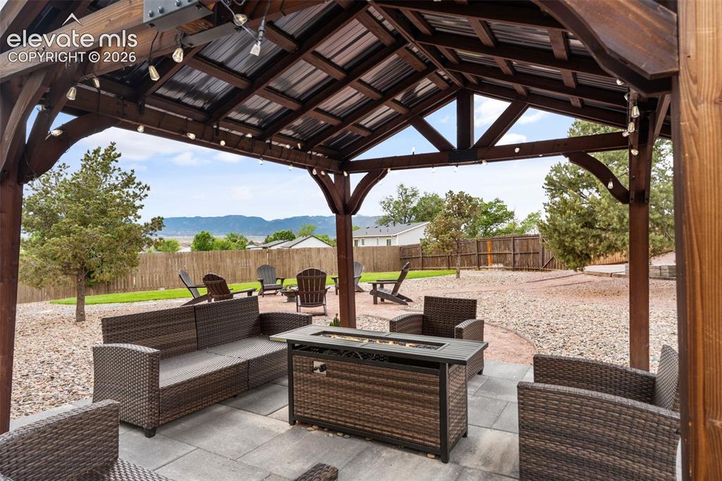 Image 34 of 43: Wood-framed gazebo with a corrugated metal roof and string lighting