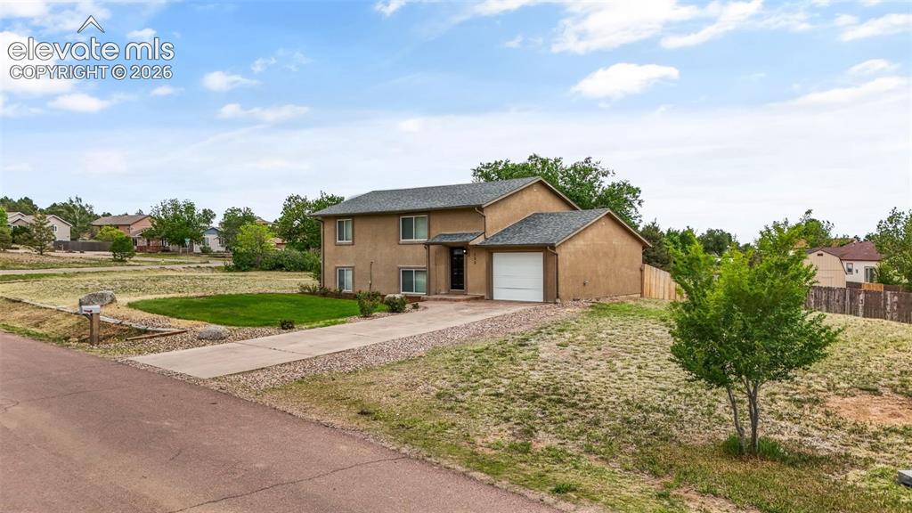 Image 4 of 43: Two-story stucco residence featuring an attached garage, a paved driveway, 