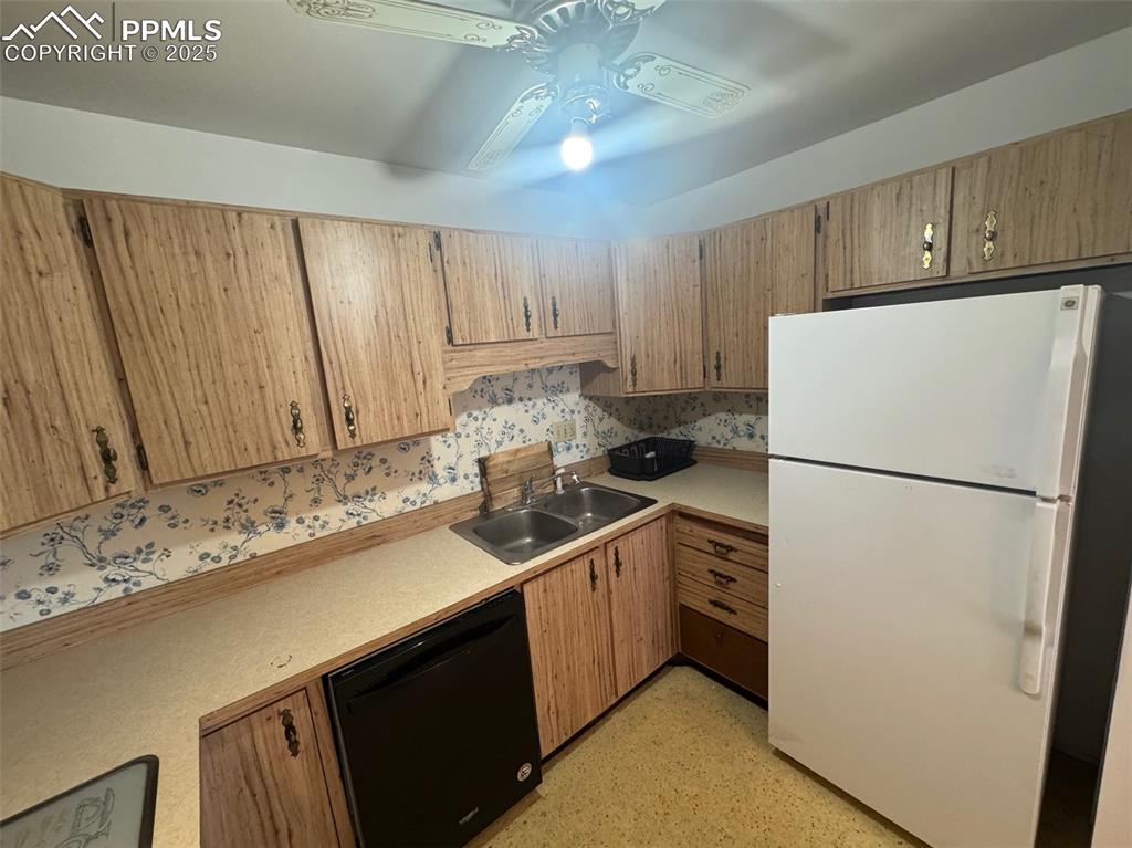 Image 7 of 30: Kitchen with freestanding refrigerator, black dishwasher, light countertops