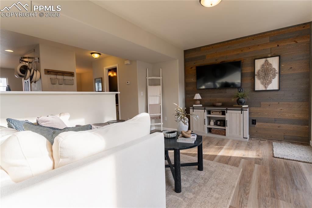 Image 12 of 23: Living area with wood walls, light wood-style floors, and an accent wall
