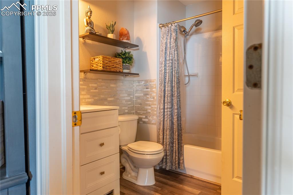 Image 15 of 23: Full bath with tile walls, dark wood finished floors, shower / tub combo, a