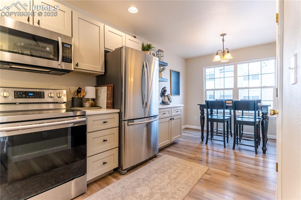 Image 6 of 23: Kitchen with stainless steel appliances, light wood-style flooring, and whi