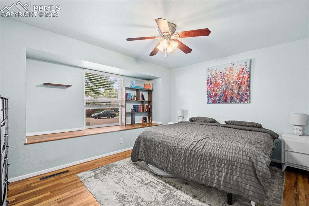 Image 11 of 33: Bedroom with wood finished floors and a ceiling fan