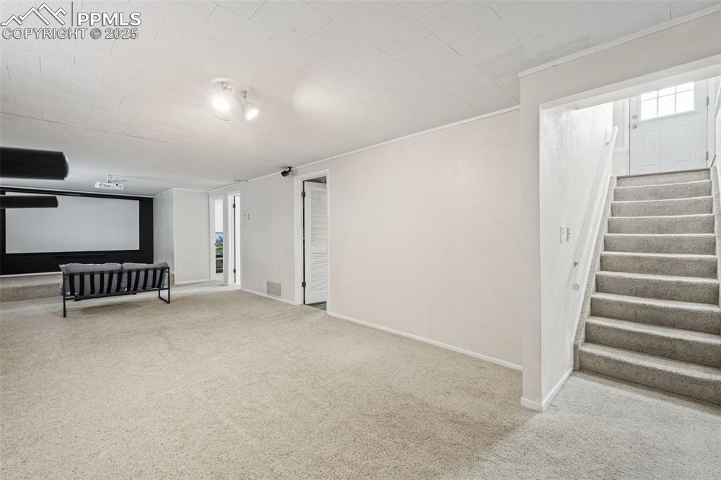 Image 17 of 33: Below grade area featuring light carpet, stairway, and plenty of natural li