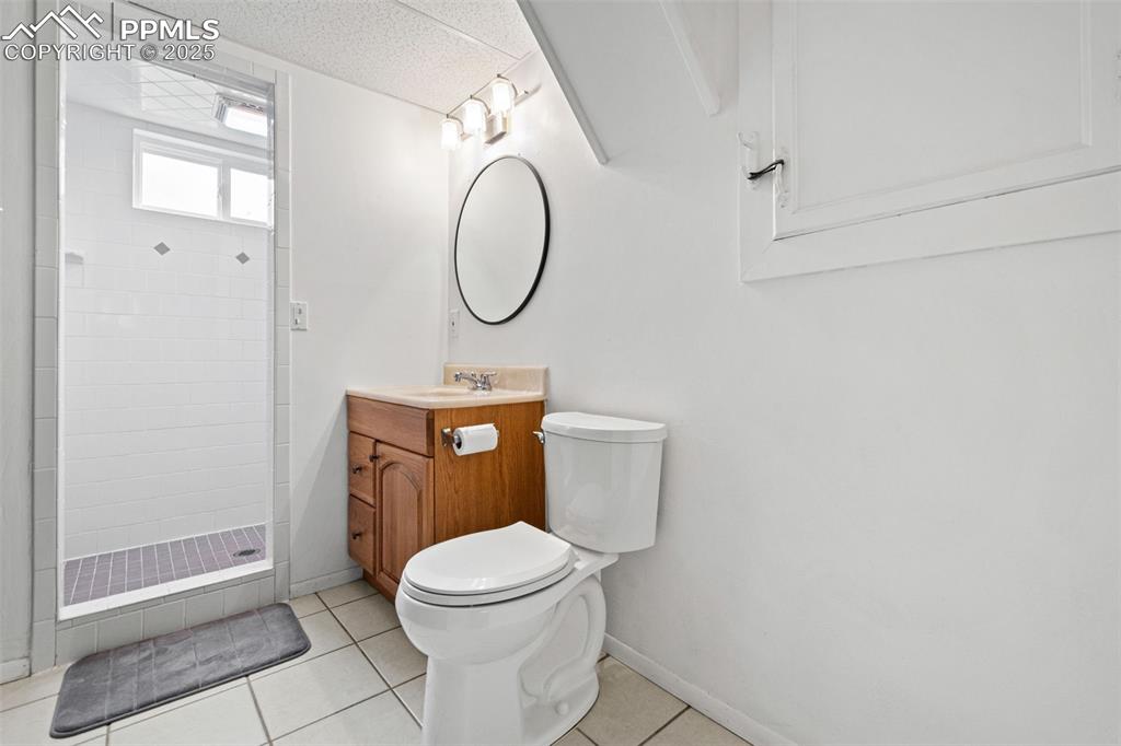 Image 24 of 33: Bathroom featuring vanity, light tile patterned floors, and a stall shower