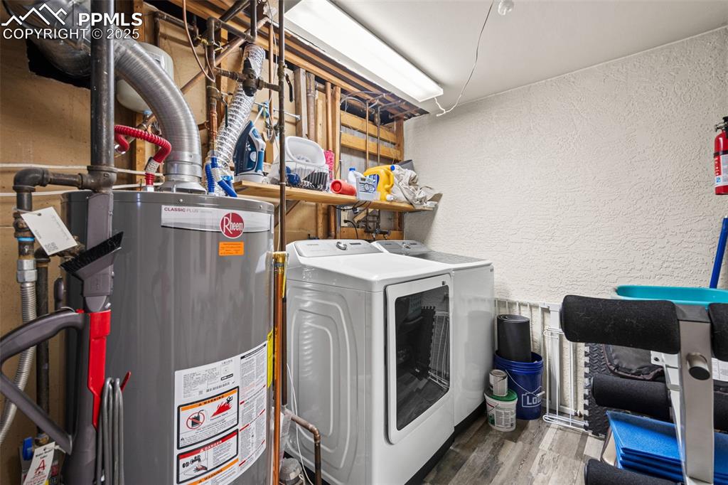 Image 25 of 33: Laundry room with a textured wall, wood finished floors, gas water heater, 