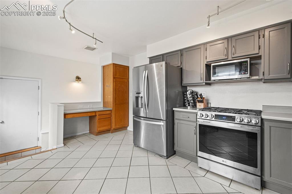 Image 8 of 33: Kitchen with appliances with stainless steel finishes, gray cabinets, light