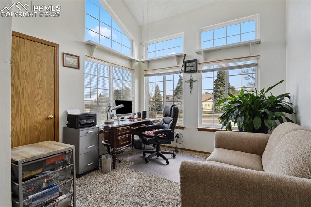 Image 12 of 18: Carpeted office space featuring baseboards and a towering ceiling