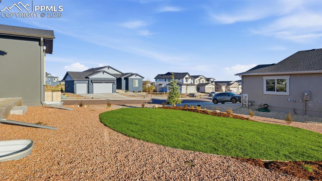 Image 46 of 50: Rear view of home and beautifully landscaped backyard with concrete patio a