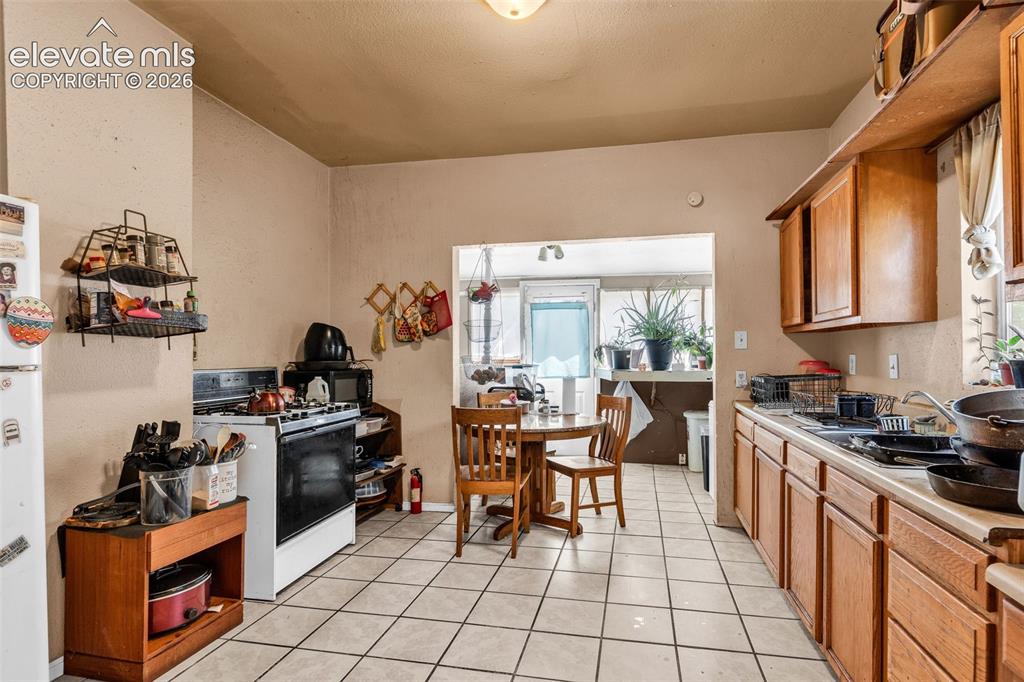 Image 11 of 31: Kitchen featuring tile flooring, wooden cabinetry, and a gas range