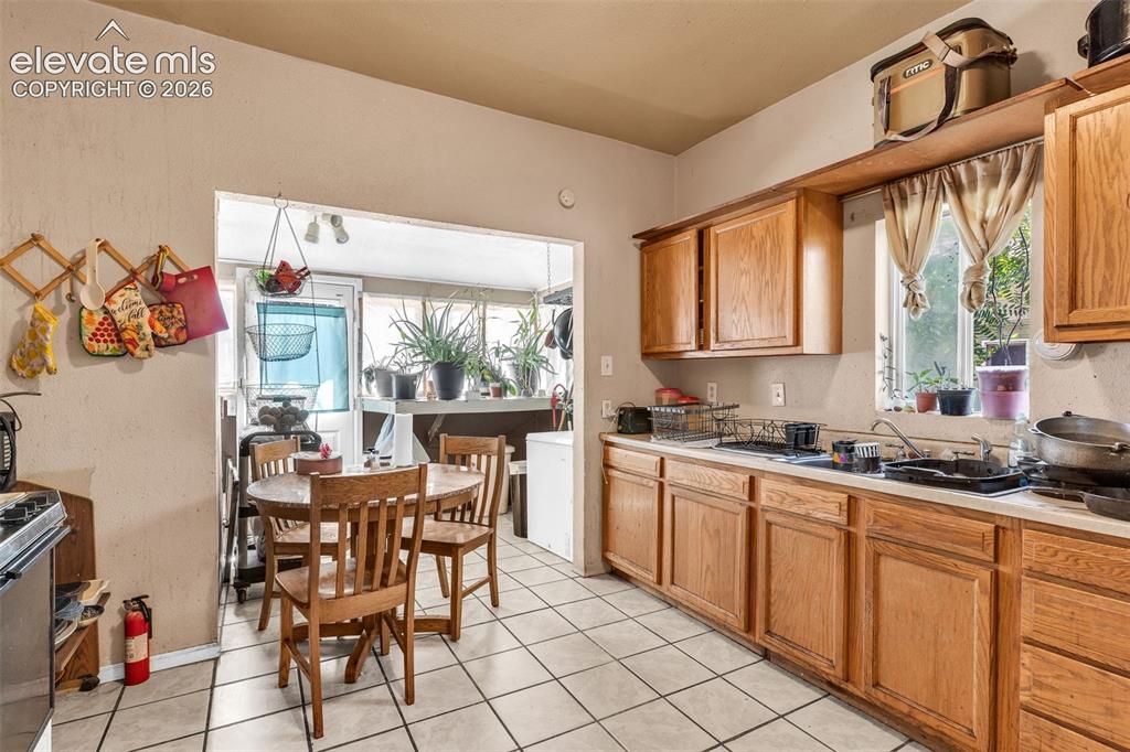 Image 12 of 31: Kitchen featuring extensive wood-finish cabinetry, white tiled flooring, an