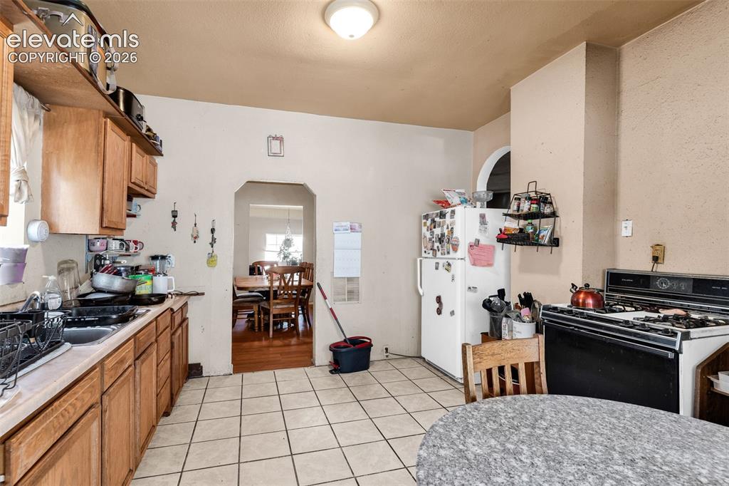 Image 13 of 31: Kitchen with wood cabinetry, light-toned countertops, and tile flooring
