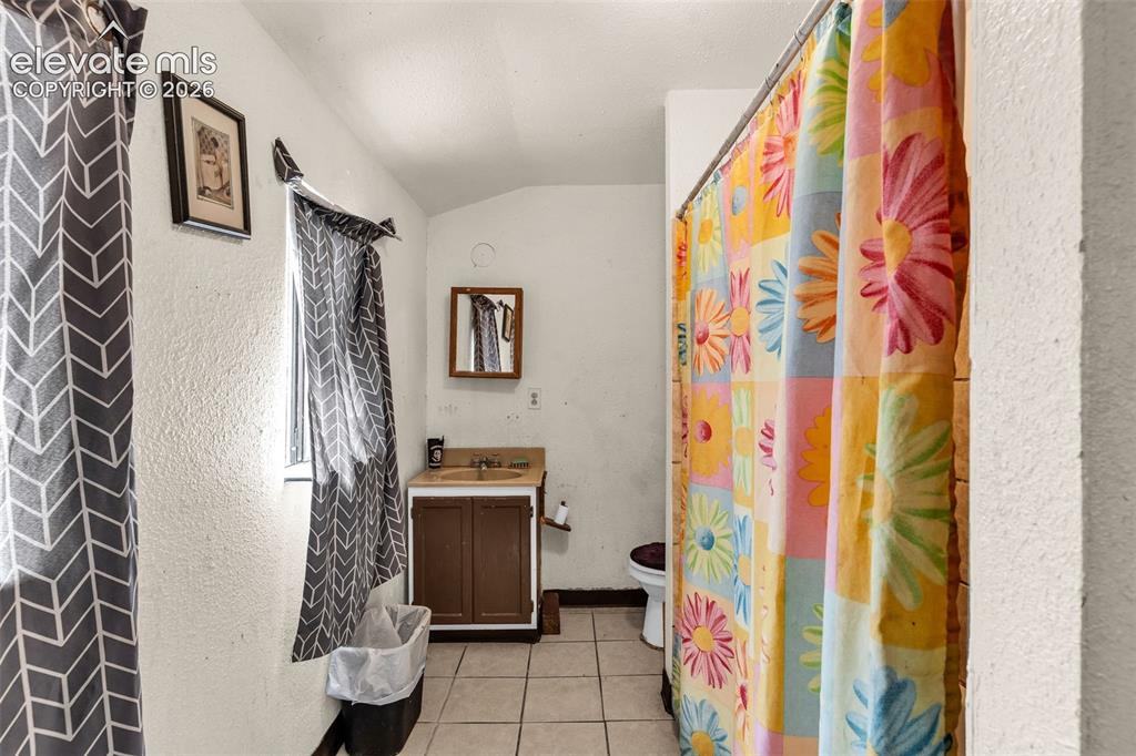 Image 19 of 31: Bathroom featuring a single-sink vanity with wood-finish cabinetry, tile fl
