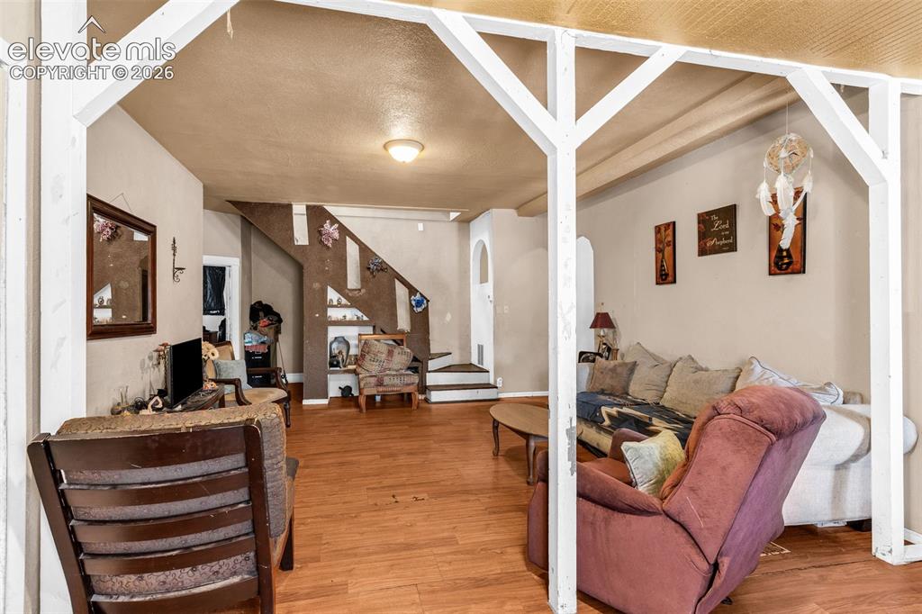 Image 4 of 31: Wood-finish flooring throughout, featuring a staircase with open shelving,