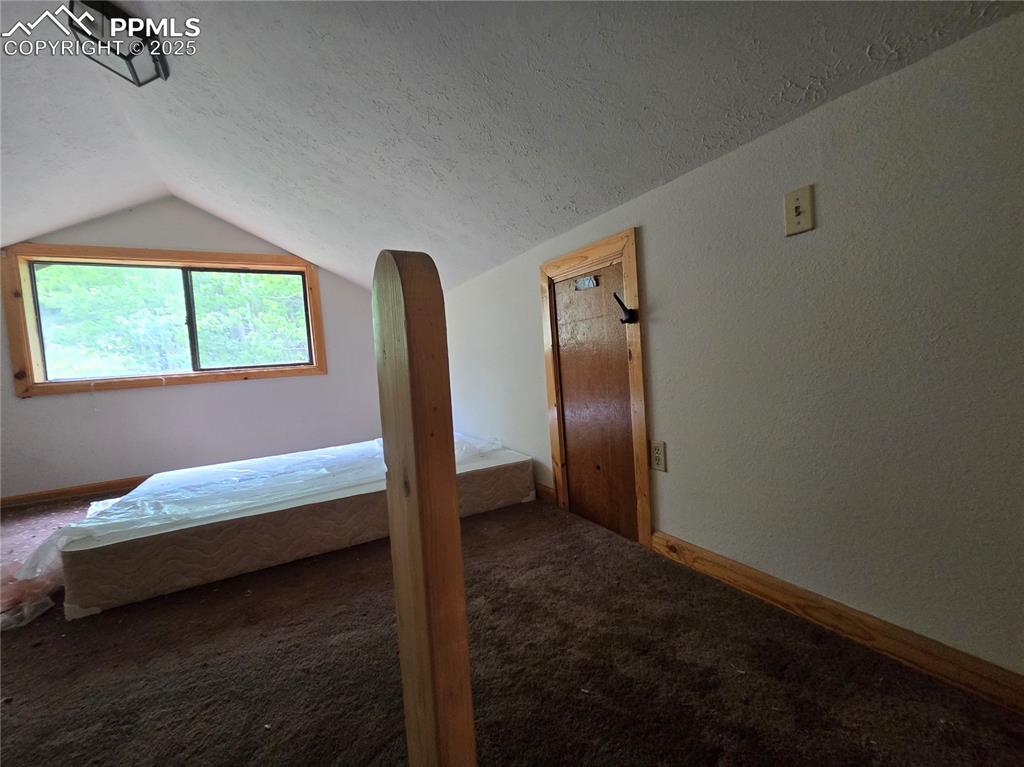Image 15 of 23: Unfurnished bedroom with lofted ceiling, a textured ceiling, carpet, and a