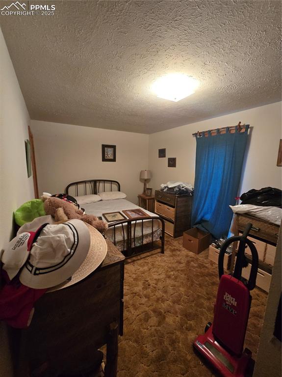 Image 5 of 23: Bedroom featuring a textured ceiling and carpet flooring