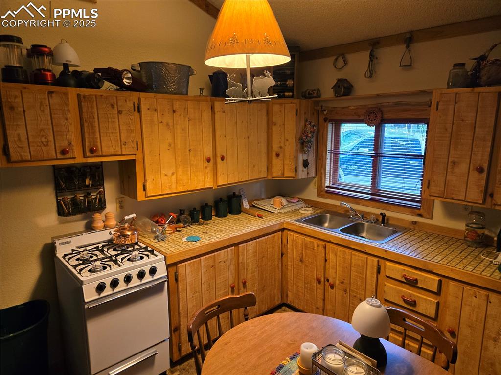 Image 8 of 23: Kitchen featuring white range with gas stovetop, tile countertops, and brow