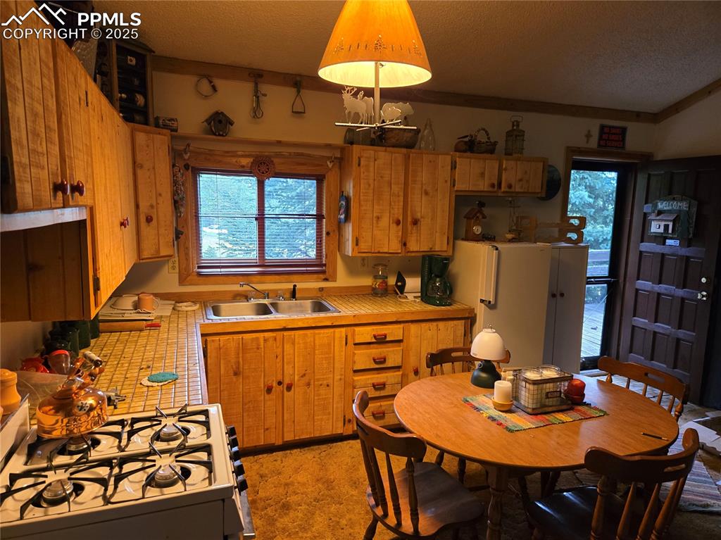 Image 9 of 23: Kitchen with gas range, freestanding refrigerator, and a textured ceiling