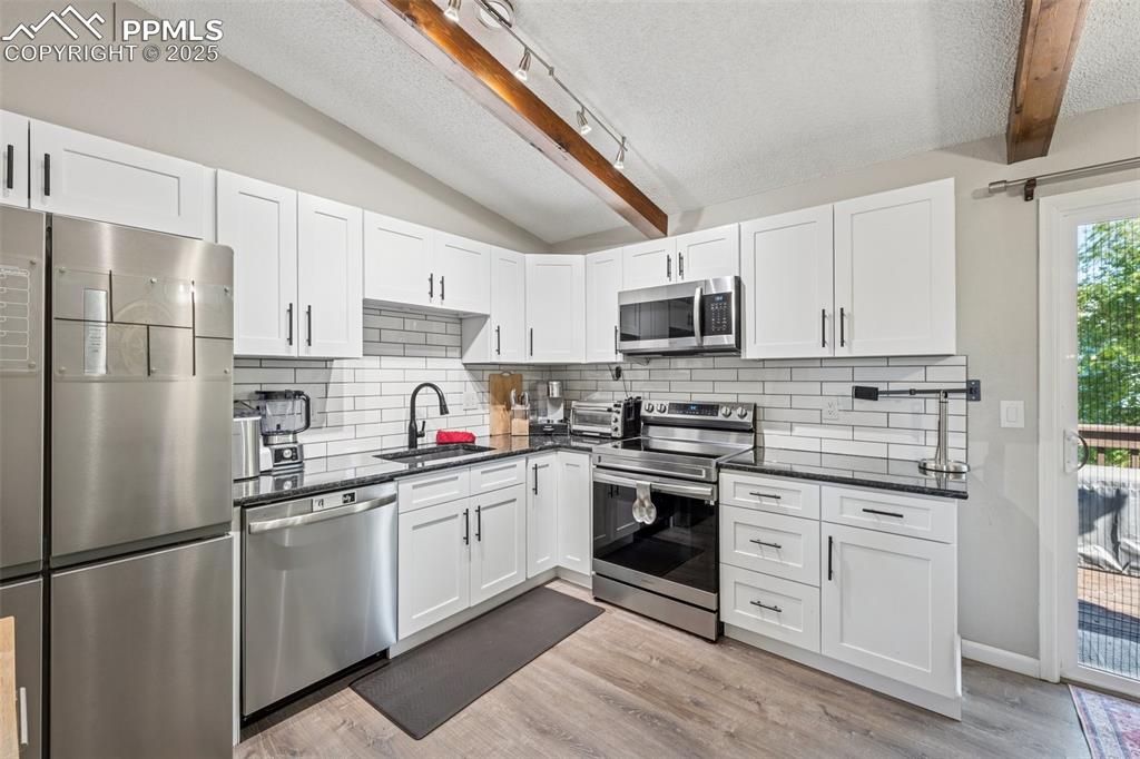 Image 12 of 25: Kitchen featuring a textured ceiling, appliances with stainless steel finis
