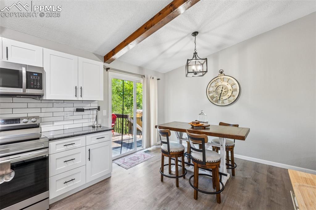 Image 13 of 25: Kitchen featuring stainless steel appliances, white cabinets, hanging light