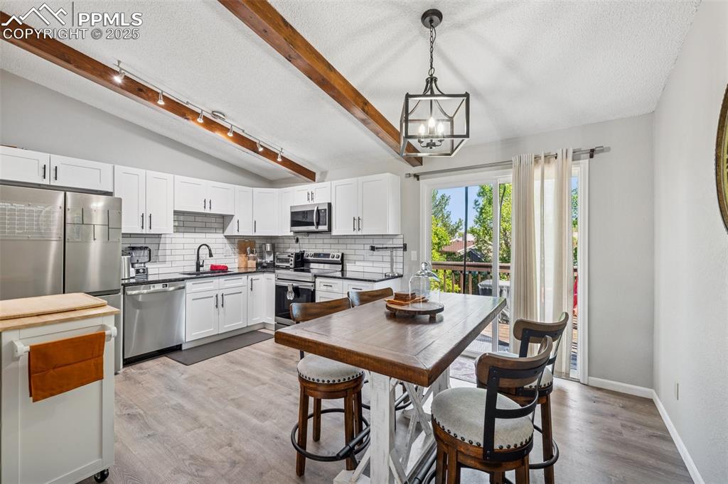 Image 15 of 25: Dining area with a textured ceiling, light wood-type flooring, a chandelier