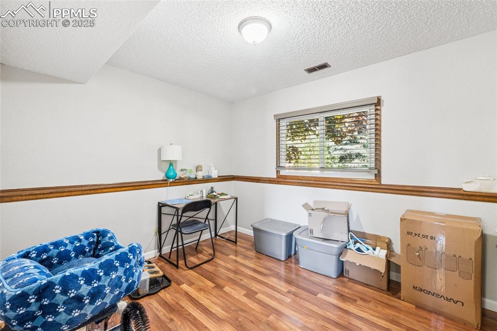 Image 17 of 25: Miscellaneous room with light wood finished floors and a textured ceiling