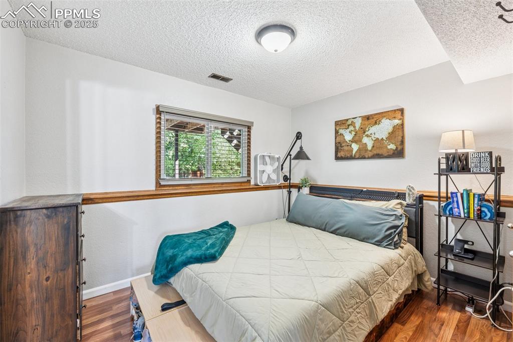 Image 18 of 25: Bedroom with wood finished floors and a textured ceiling lower level