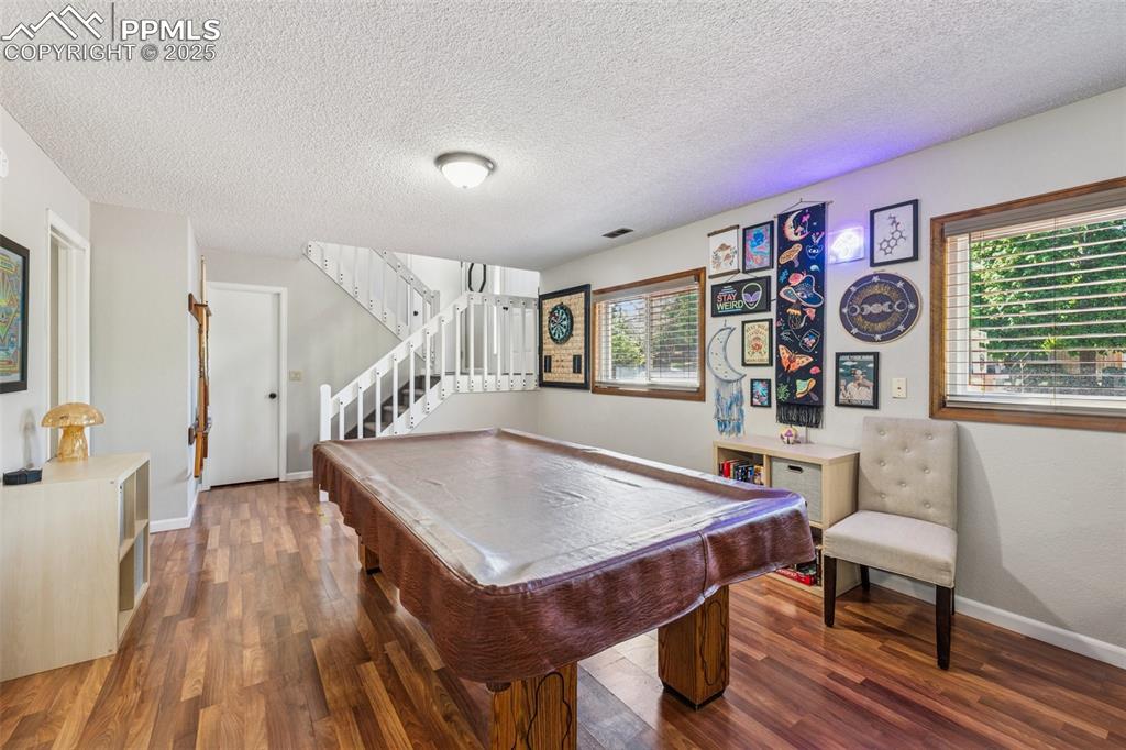 Image 19 of 25: Rec room with a textured ceiling, billiards, and wood finished floors