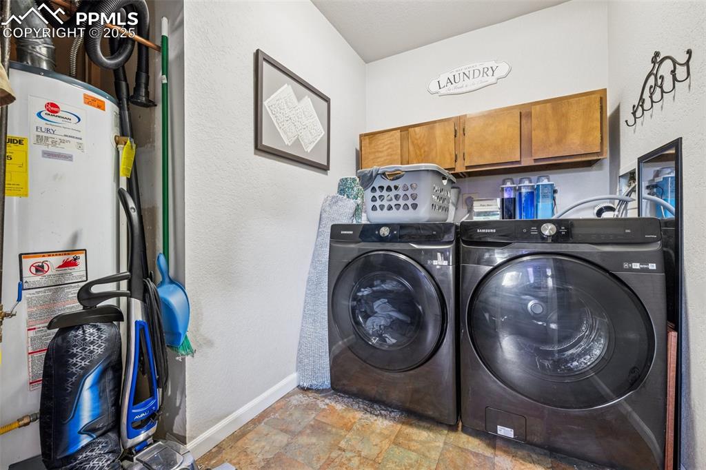 Image 21 of 25: Laundry room featuring a textured wall, stone finish flooring, gas water he