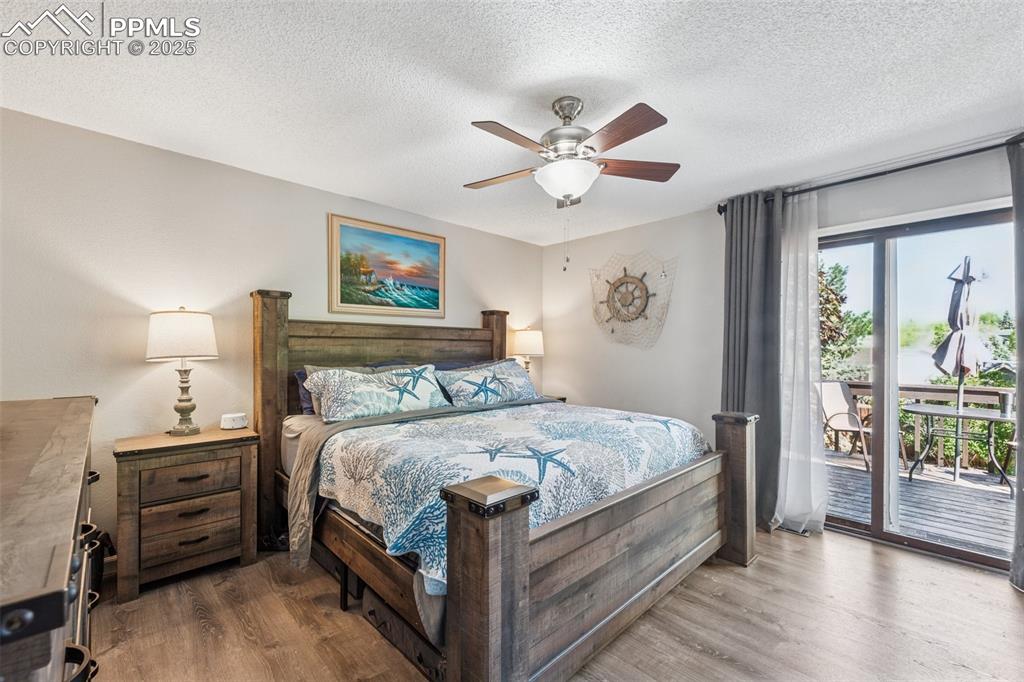 Image 4 of 25: Bedroom with access to exterior, wood finished floors, a textured ceiling,