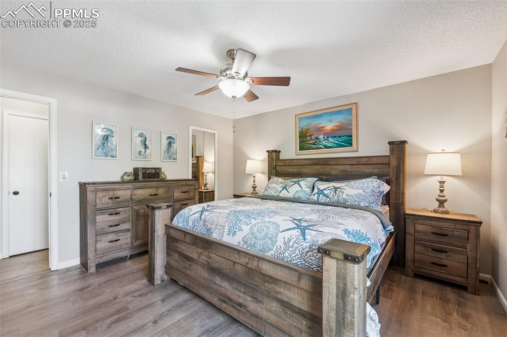 Image 5 of 25: Bedroom featuring wood finished floors, a textured ceiling, and a ceiling f